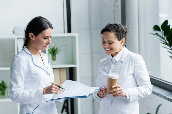 Smiling African American Doctor Coffee Standing Colleague Clipboard Clinic — Stock Photo, Image