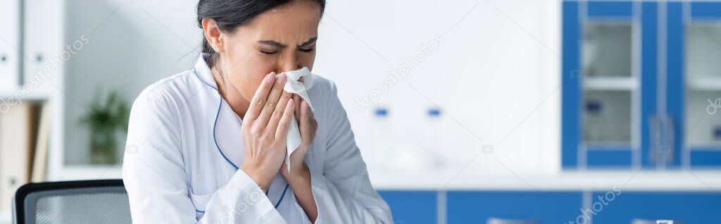 Doctor in white coat sneezing in clinic, banner 