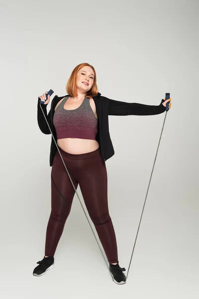 Sonriente Deportista Talla Grande Sosteniendo Cuerda Saltando Sobre Fondo Gris — Foto de Stock