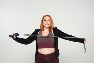 Genç vücut pozitifliği olan sporcu kadın gri ipte yalıtılmış halat tutuyor. 