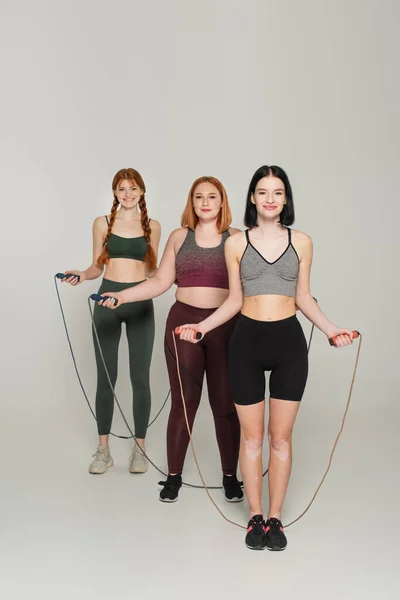 Deportistas Felices Cuerpo Positivo Sosteniendo Cuerdas Salto Sobre Fondo Gris — Foto de Stock