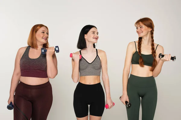 Sportvrouwen Training Met Halters Kijken Naar Sproeten Vriend Geïsoleerd Grijs — Stockfoto