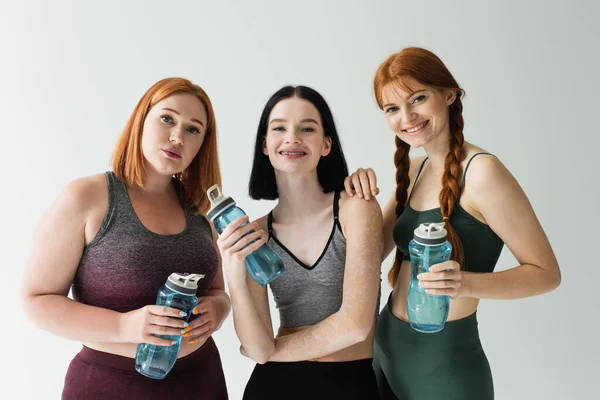 Deportistas Sonrientes Con Botellas Deportivas Aisladas Gris — Foto de Stock