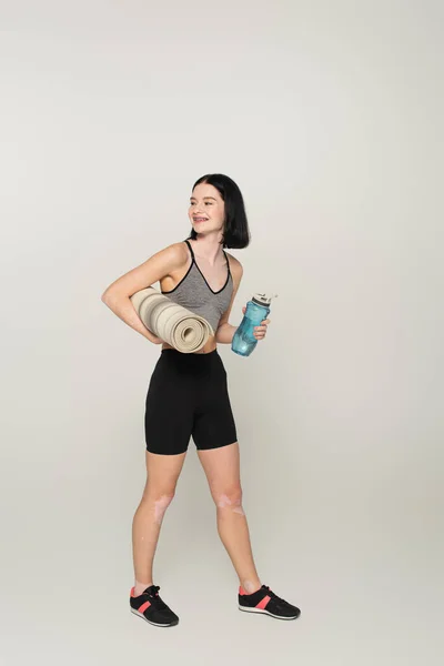 Cheerful Sportswoman Vitiligo Holding Sports Bottle Fitness Mat Grey Background — Stock Photo, Image