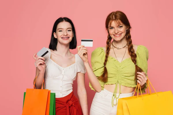 女性の笑顔でそばかすとVitiligo示すクレジットカードと保持ショッピングバッグでピンクの背景 — ストック写真