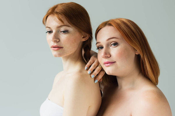 Red haired women with naked shoulders standing isolated on grey 