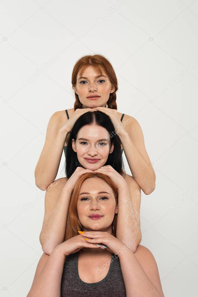 Young body positive sportswomen looking at camera isolated on grey 