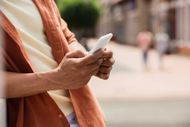 cropped view of african american man using smartphone outdoors clipart