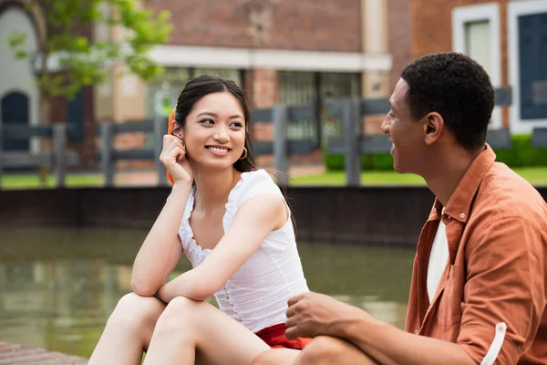 Feliz Pareja Multicultural Hablando Mientras Está Sentado Calle Urbana — Foto de Stock