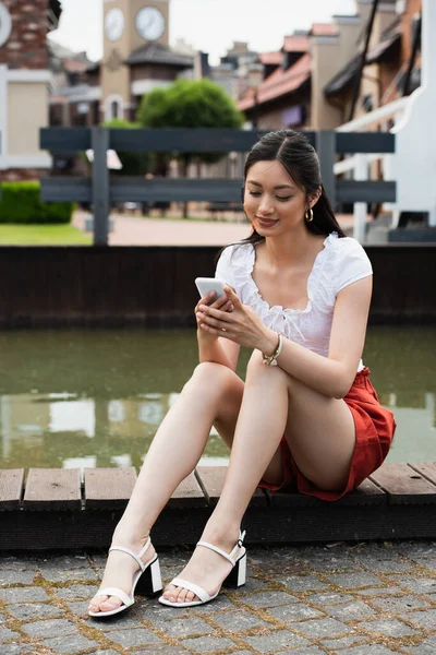 Smiling Asian Woman Sitting Border Water Using Smartphone — Stock Photo, Image