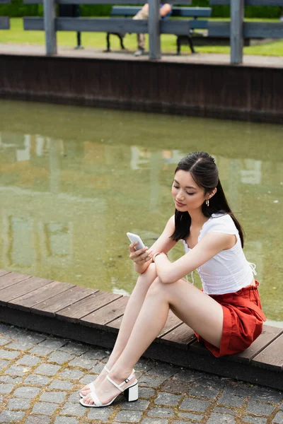 Young Asian Woman Looking Mobile Phone While Sitting Border Water — Stock Photo, Image