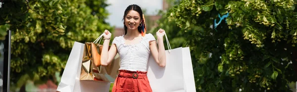 Stylish Asian Woman Holding Shopping Bags While Smiling Camera Green — Stock Photo, Image