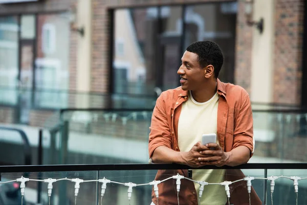 Hombre Afroamericano Sonriente Con Teléfono Inteligente Mirando Hacia Otro Lado — Foto de Stock