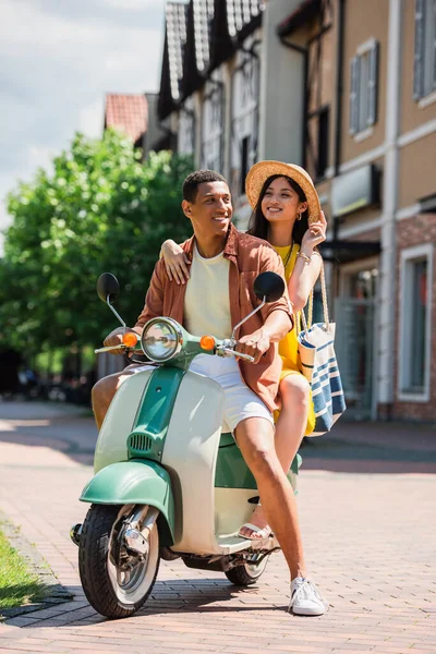 スタイリッシュな異人種間のカップルが街中のスクーターで — ストック写真