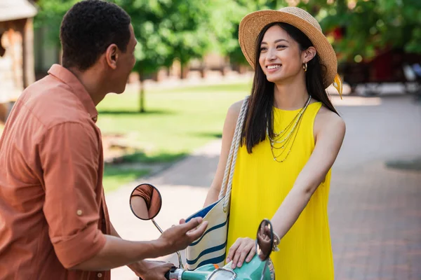 African American Man Gesturing While Talking Asian Woman Straw Hat — Stok Foto