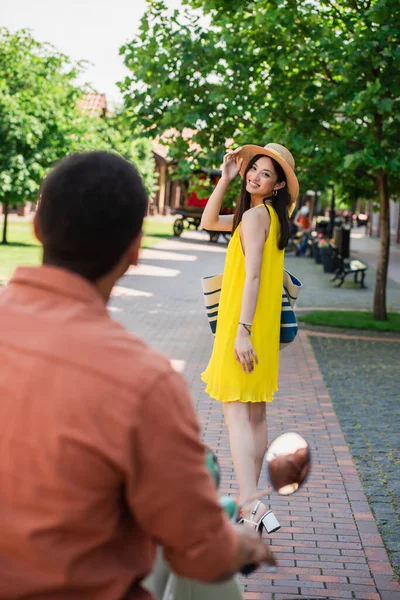 Stylish Asian Woman Touching Straw Hat While Smiling African American — Stock Photo, Image