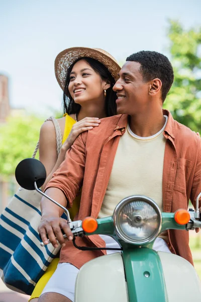 若いアフリカ系アメリカ人の男性がアジア系の女性とスクーターに乗って — ストック写真