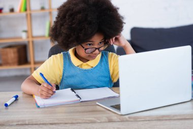 Evde eğitim görürken dizüstü bilgisayara bakan Afrikalı Amerikalı çocuk. 