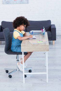 Afro-Amerikan çocuğun evdeki deftere yazı yazışının yan görüntüsü 