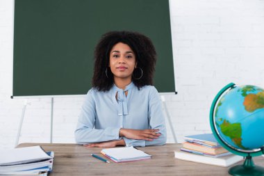 Sınıfta çalışma masasında oturan Afrikalı Amerikalı öğretmen 