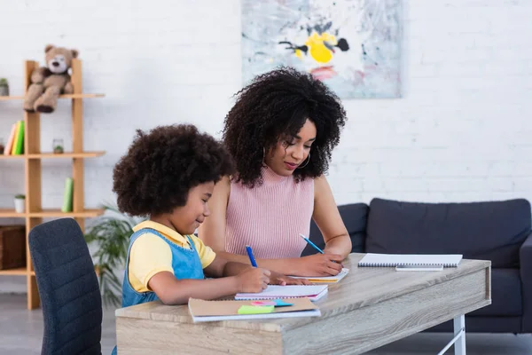 Glimlachend Afrikaans Amerikaans Kind Schrijven Notebook Buurt Van Ouder Thuis — Stockfoto