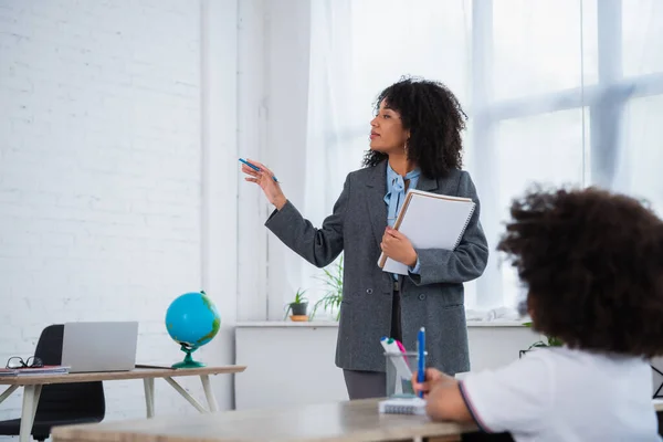 Profesora Afroamericana Apuntando Con Mano Cerca Alumno Borroso Aula — Foto de Stock