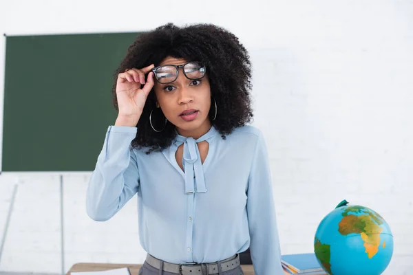 Amazed African American Teacher Holding Eyeglasses Looking Camera Classroom — Stock Photo, Image