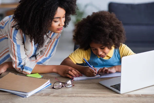 African American Mother Standing Kid Writing Notebook Laptop Homeschooling — Stock Photo, Image