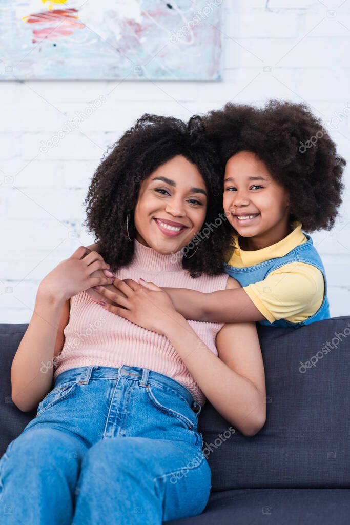 Happy african american kid hugging mother at home 