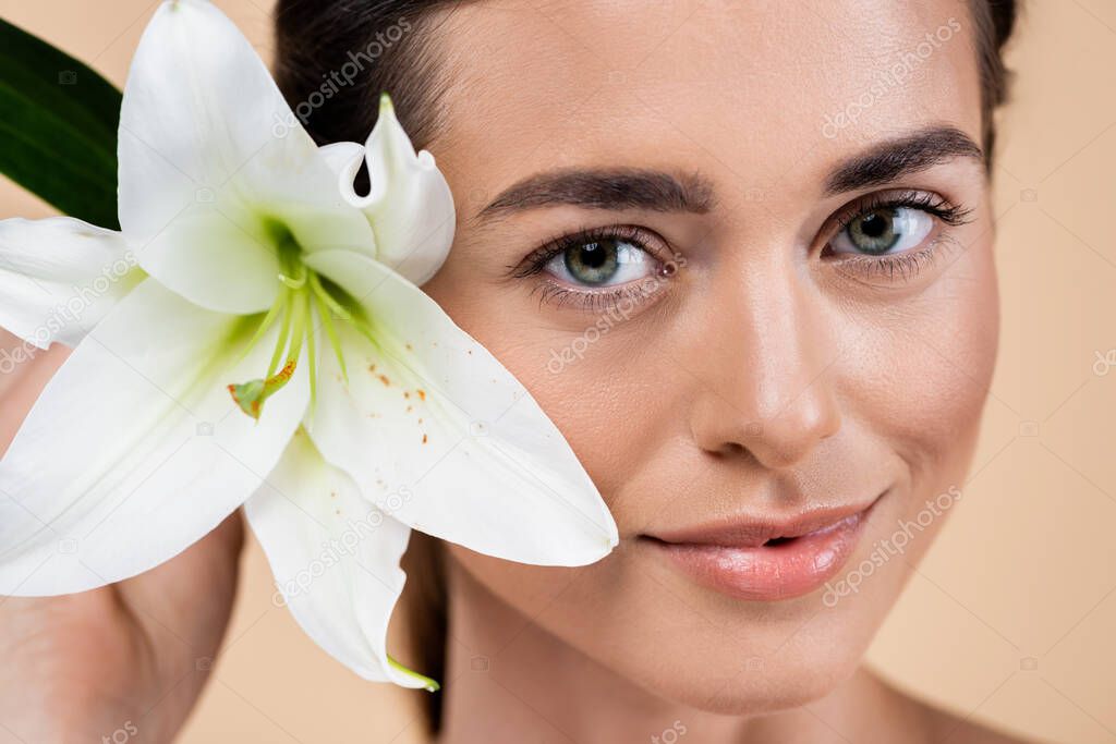 close up portrait of young woman with perfect face near lily flower isolated on beige, beauty concept