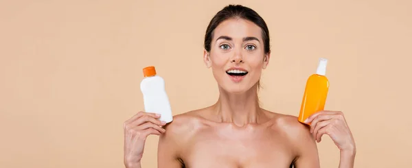 Amazed Woman Showing Bottles Sunblock While Looking Camera Isolated Beige — Φωτογραφία Αρχείου