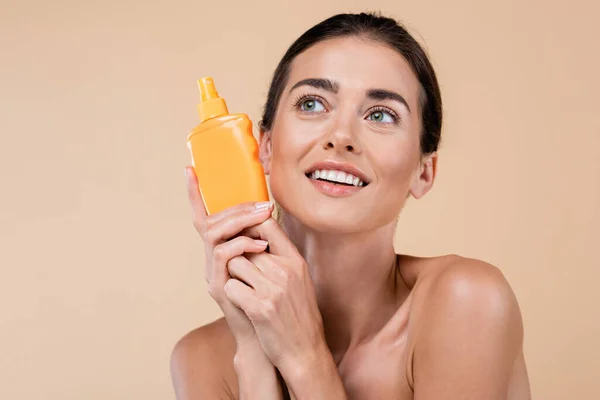 Smiling Woman Orange Bottle Sunblock Looking Away Isolated Beige — Φωτογραφία Αρχείου