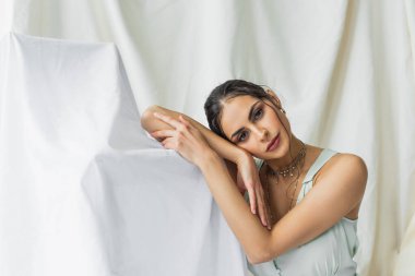 Beyaz elbiseli güzel kadın kameraya bakıyor.