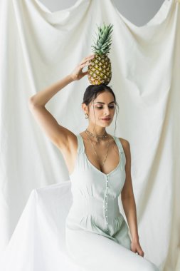 Kafasının üstünde ananas tutan esmer kadın. 