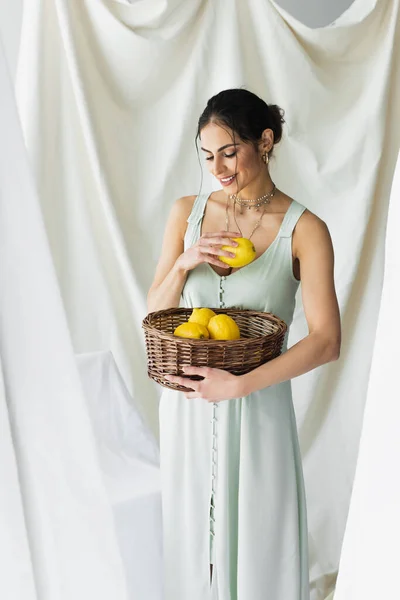 Mujer Complacida Vestido Sosteniendo Limones Maduros Canasta Mimbre Blanco — Foto de Stock