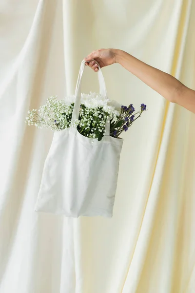 白い花のある生地の買い物袋を持っている女性のクロップドビュー — ストック写真