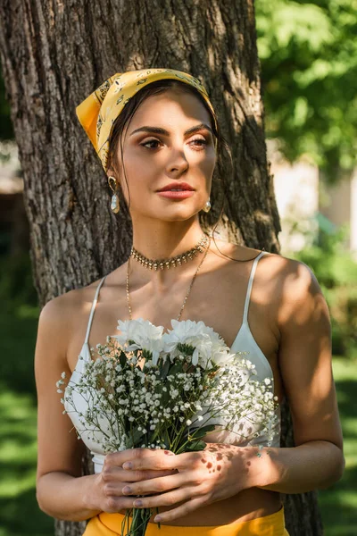 Stylische Frau Mit Gelbem Kopftuch Hält Blumen Neben Baum — Stockfoto