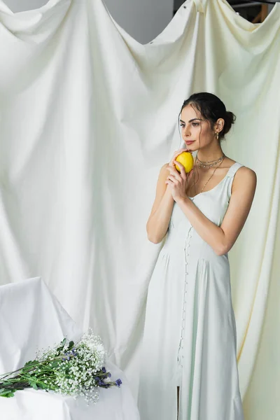 Donna Sognante Abito Che Tiene Limone Vicino Mazzo Fiori Bianco — Foto Stock