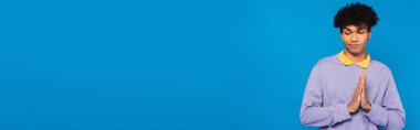 confused african american man showing please gesture isolated on blue, banner