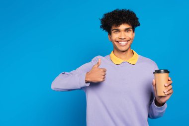 pleased african american man with takeaway drink showing like isolated on blue