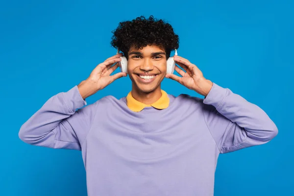 Happy African American Man Adjusting Wireless Headphones Isolated Blue — Fotografia de Stock