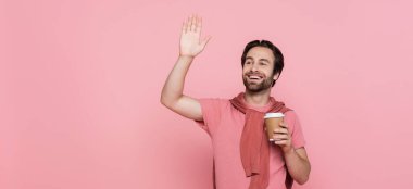 Pozitif adam elinde kağıt bardakla pembe pankartta el sallıyor. 