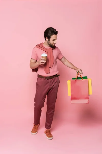 Man Takeaway Cup Looking Shopping Bags Pink Background — Stock Photo, Image