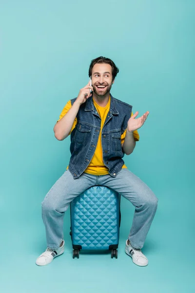 Sonriente Hombre Hablando Teléfono Celular Mientras Está Sentado Maleta Sobre — Foto de Stock