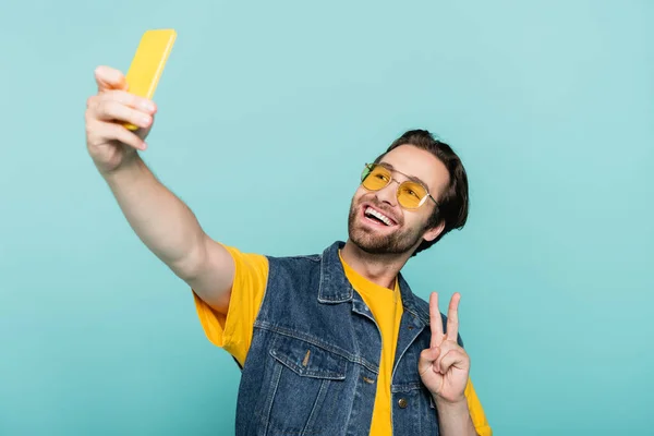 Hombre Sonriente Chaleco Vaquero Mostrando Signo Paz Mientras Toma Selfie —  Fotos de Stock