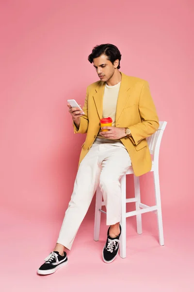 분홍색 의자에 의자에 핸드폰을 사용하고 청년의 — 스톡 사진