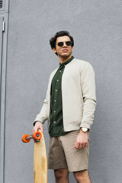 Homem Elegante Óculos Sol Segurando Longboard Perto Edifício — Fotografia de Stock