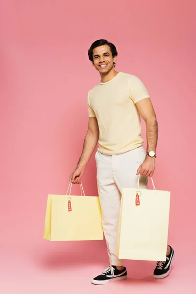 Full Length Cheerful Young Man Holding Shopping Bags Sale Tags — Stock Photo, Image