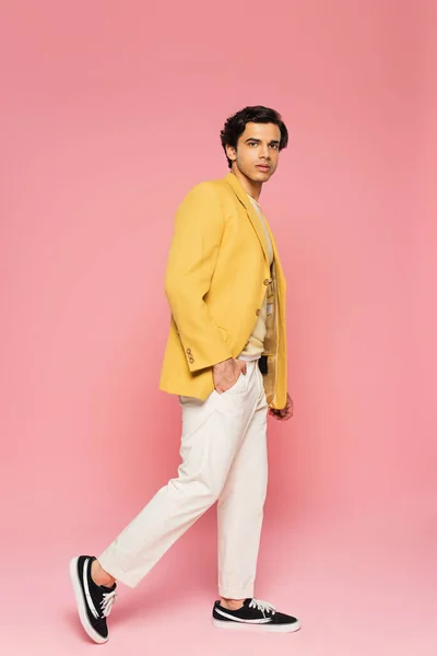 全身上下穿着时髦的黄色夹克 手插在口袋里 与粉色隔离的年轻人 — 图库照片