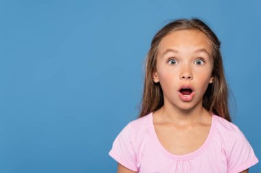 Astonished girl in pink t-shirt looking at camera isolated on blue  clipart